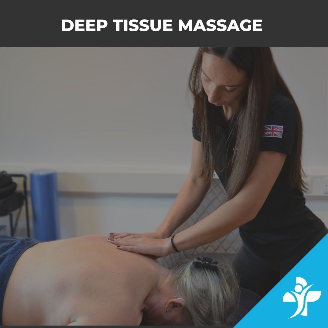 Therapist performs a deep tissue massage on a client lying face down, hands pressing along the back in a treatment room with a blue mat in the background.