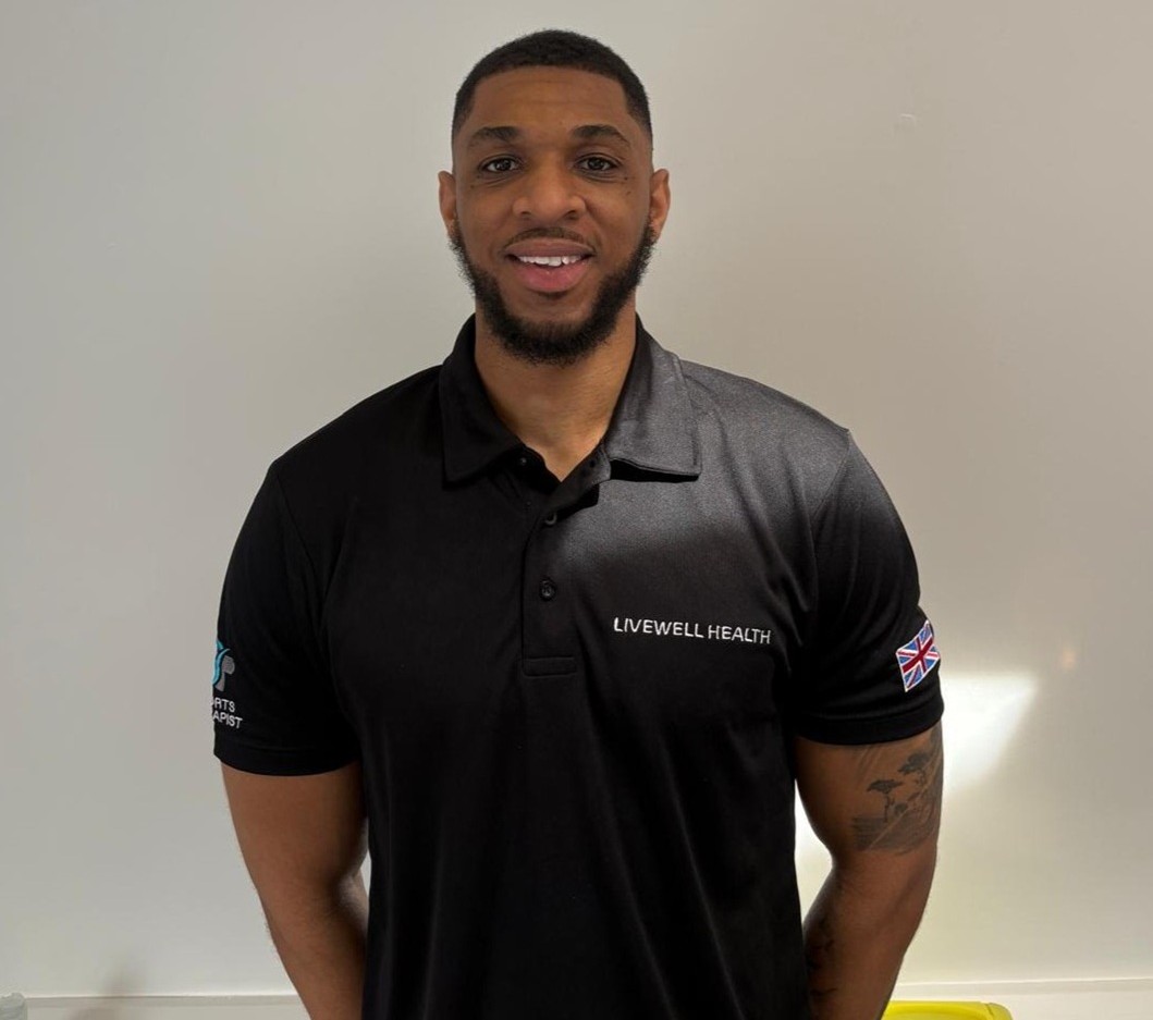 Portrait of a smiling man in a black Livewell Health polo with UK flag patch on the sleeve.